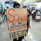 A protester shows a placard to stranded travelers during a demonstration at the Airport in Hong Kong earlier this week